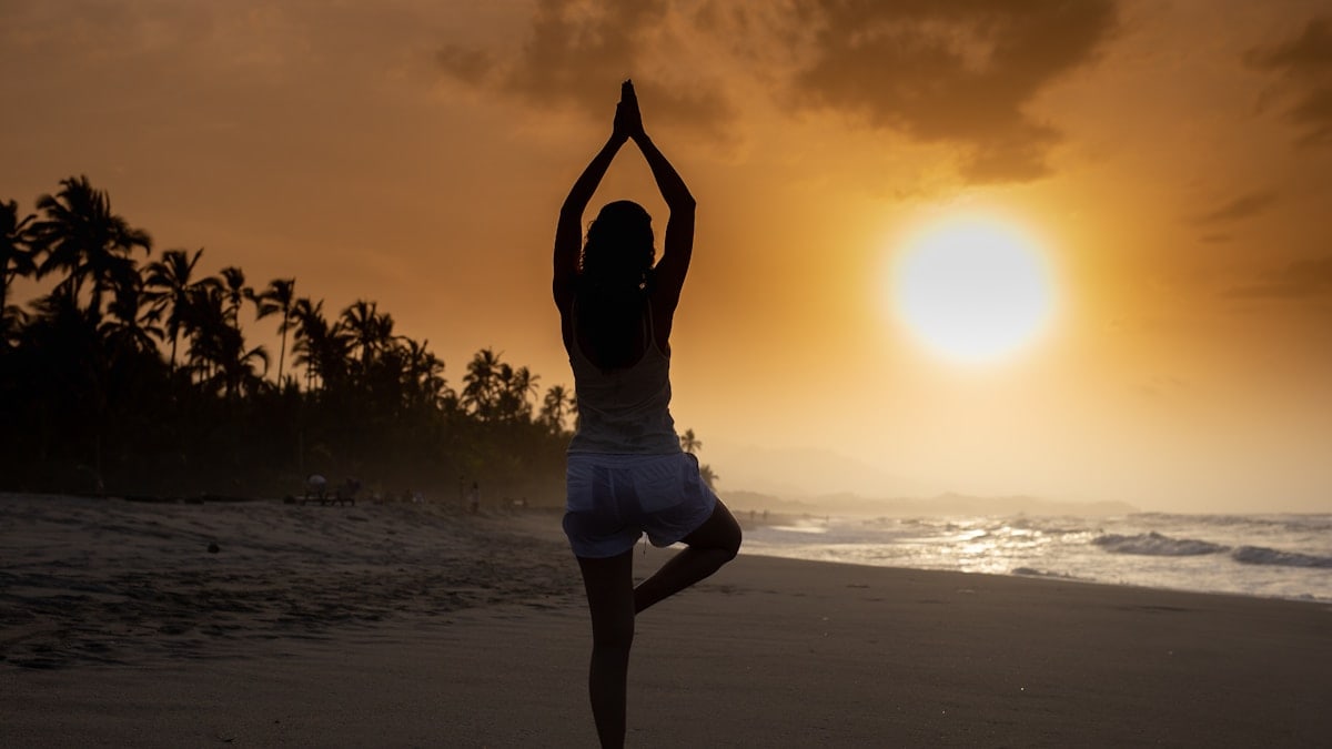 woman in white tank top and white shorts standing on beach during sunset